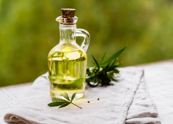 CBD oil hemp products. Essential oil of medicinal cannabis in a bottle with fresh leaves from marijuana. Selective soft focus. Close up - 写真・画像