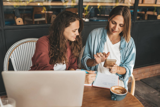 Two women discussing business projects in a cafe while having coffee. Startup, ideas and brain storm concept - Photo, Image