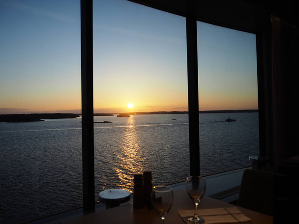 Kontrastlı ışık, Norveç fiyortlarında gün batımında bir restoranda bir yolcu gemisinin geniş penceresinden bakmak. Yolcu gemisi. Norveç fiyortlarındaki yolcu gemisinin içinden bakıyorum.. - Fotoğraf, Görsel