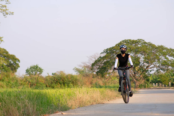 Sportliches Mädchen fährt Fahrrad auf der Straße im Hintergrund der Natur - Foto, Bild