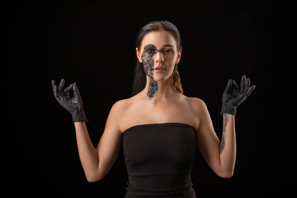 Muotokuva nuori aistillinen brunette nainen musta korppi lintu kehon taidetta hänen kasvonsa. Nainen yllään mustat käsineet
 - Valokuva, kuva