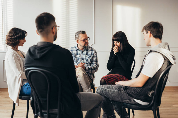 Group of people of different ages sits in a circle during a meeting with a professional therapist - Photo, Image