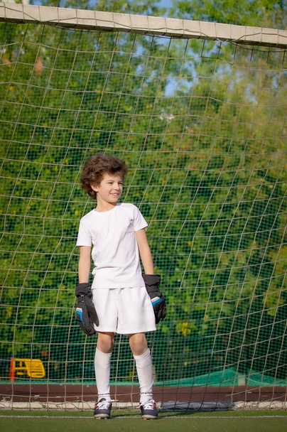 Summer soccer tournament for young kids. football club. emotions and joy of the game. Young goalie. Kids - soccer champion. Boy goalkeeper in football sportswear on stadium with ball. Sport concept. - Fotografie, Obrázek