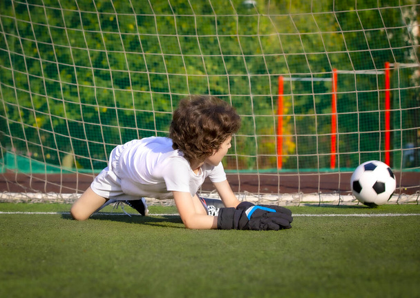 junior soccer goalkeeper. Disappointed boy in white goalie sportswear. Goalkeeper missed a goal during friendly match. - Foto, Bild