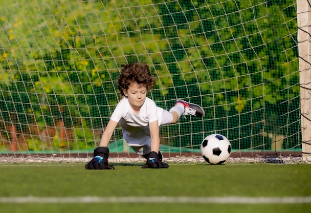 Summer soccer tournament for young kids. football club. emotions and joy of the game. Young goalie. Kids - soccer champion. Boy goalkeeper in football sportswear on stadium with ball. Sport concept. - Фото, зображення