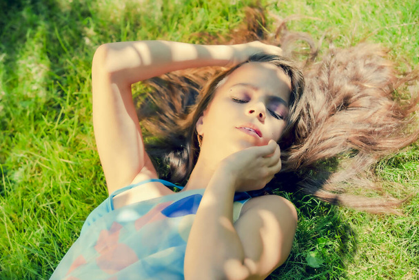 girl teenager in a swimsuit laying on a green grass of a lawn on the sea coast - Photo, Image