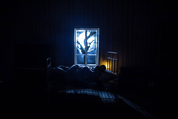 Man comfortably sleeping in his bed at night. A realistic dollhouse bedroom with furniture and window at night. Selective focus - Photo, Image