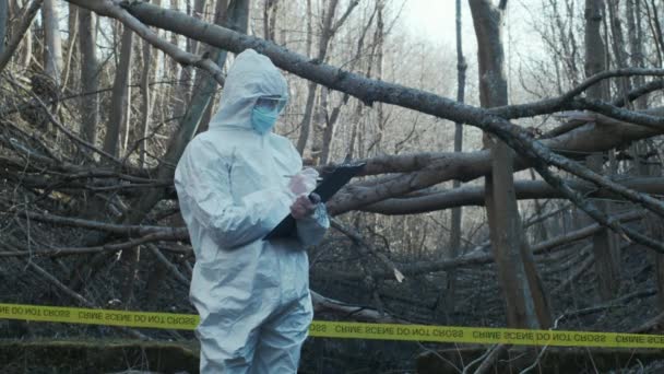 Forensic specialist working in the forest. Police criminalists collecting evidence and making criminal investigation. Crime scene concept. - Filmati, video