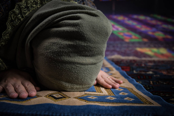 Μουσουλμάνα γυναίκα προσεύχεται για τον Αλλάχ μουσουλμάνο θεό στο τζαμί. Χέρια μουσουλμάνων γυναικών στο χαλί προσεύχεται με παραδοσιακά ρούχα, γυναίκα σε Hijab. - Φωτογραφία, εικόνα