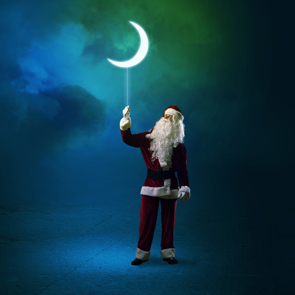 Joulupukki pitelee loistavaa kuuta
 - Valokuva, kuva