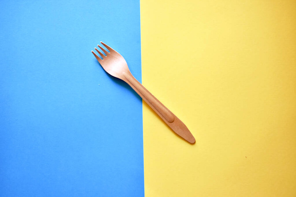 Tenedor de madera ecológico sobre fondo azul amarillo
  - Foto, Imagen