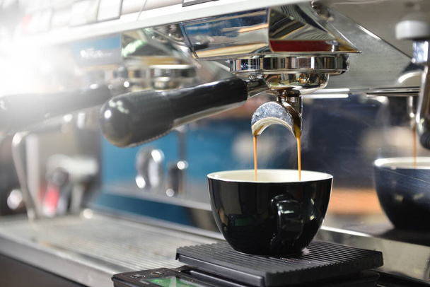Kahve yaparken büyük kahve makinesi ve siyah kupa. Küçük işletme kavramı - Fotoğraf, Görsel