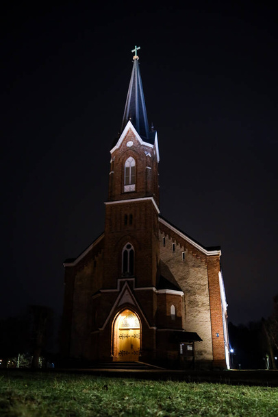 Akşamın ilerleyen saatlerinde aydınlatılmış ışıklarla güzel bir yerel kilise manzarası. Fotoğraf Avrupa, Letonya 'da çekildi. - Fotoğraf, Görsel