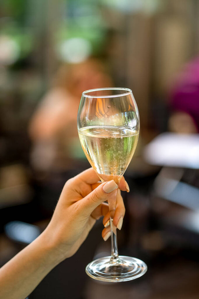 Glass of white wine in woman hand on terrace bokeh - 写真・画像