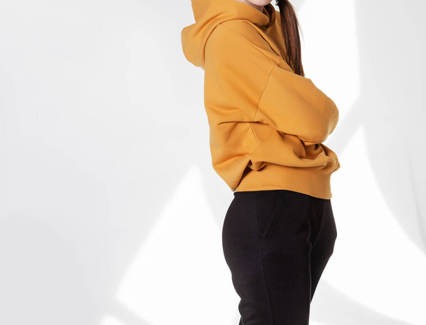 Young girl wearing blank sweatshirt and and sport pants. Gray wall background shadow light from the window with copy space for your text message or promotional content - Φωτογραφία, εικόνα