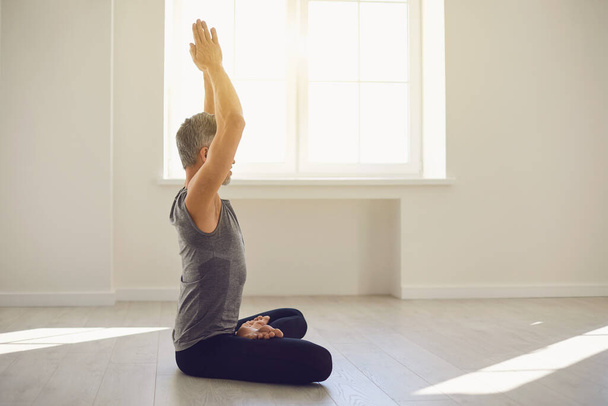 Yoga man. Bearded guy is practicing yoga in a lotus position sitting in a studio - Zdjęcie, obraz