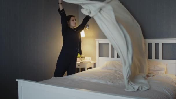 Young woman in black pajamas makes the bed in bedroom - Filmagem, Vídeo