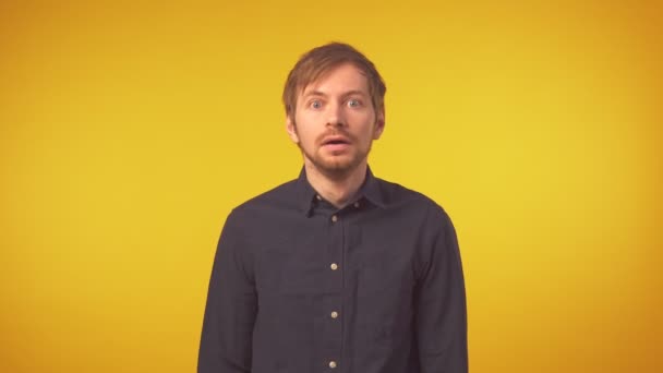 Porträt eines geschockten Mannes mit den Händen im Gesicht vor gelbem Hintergrund - Filmmaterial, Video