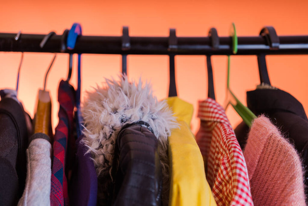 Close up of hangers with clothes on orange background. - Foto, imagen