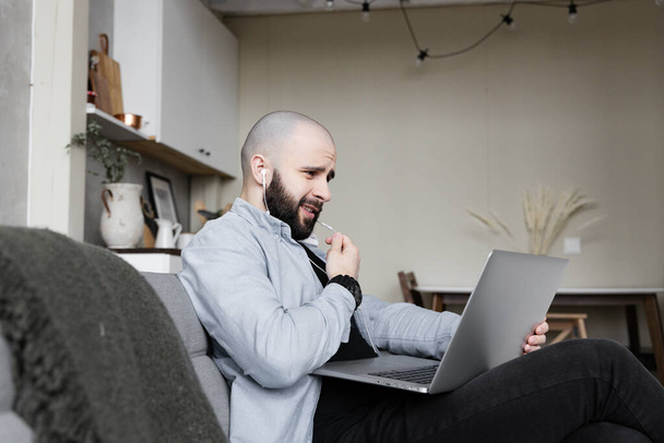 Egy szakállas és inges brutális fickó részt vesz egy videokonferencián otthonról. A munka és a tanulás fogalma online - Fotó, kép