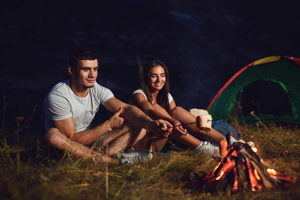 Young couple tourists on camping night cook bread by campfire - Foto, Bild