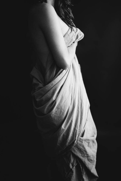 μαύρο και άσπρο στούντιο πορτρέτο ενός όμορφου κοριτσιού σε λευκό σεντόνι, όμορφο γυναικείο σώμα, μόδα και τέχνη - Φωτογραφία, εικόνα