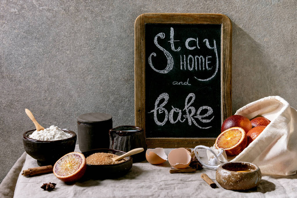 Ingredients for baking. Stay home quarantine isolation period concept. Vintage chalkboard with handwritten chalk lettering Stay home and bake. Grey texture background - Foto, Bild