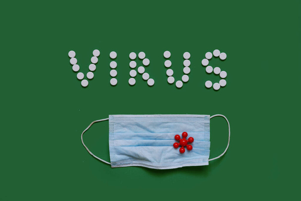 VIRUS inscription from white pills on black background with a medical mask - Photo, image