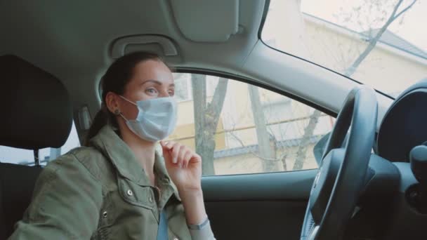 Wonderful Caucasian young brunette girl in green winter jacket wear a blue protection medical face mask on sunny day. Happy woman with brown ponytail hair  driver dancing in a car close up. Inside view.  - Filmagem, Vídeo