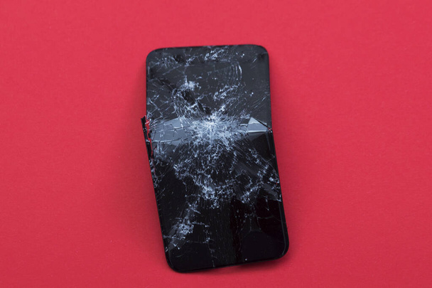 Broken in half screen phone on a red background. - Valokuva, kuva