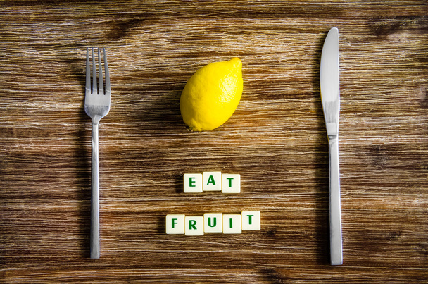 Silverware and lemon on wooden table with sign Eat fruit - Photo, Image