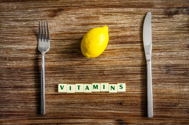 Besteck und Zitrone auf Holztisch mit Vitaminzeichen - Foto, Bild