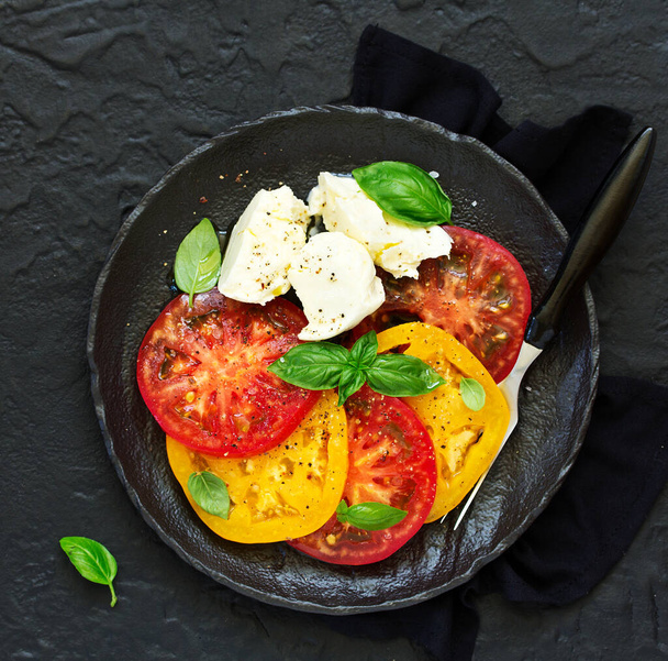 salad of yellow and red tomatoes with mozzarella. . - Фото, изображение
