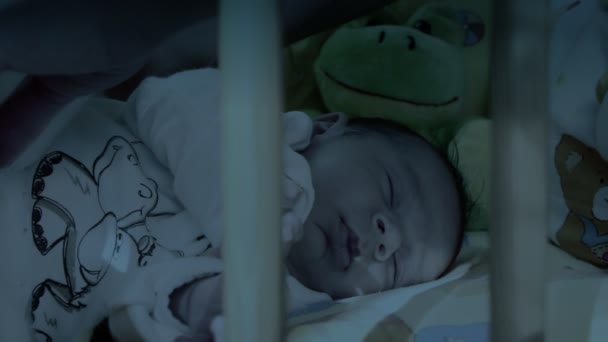 Mother kissing her sleeping baby, night shot - Filmati, video