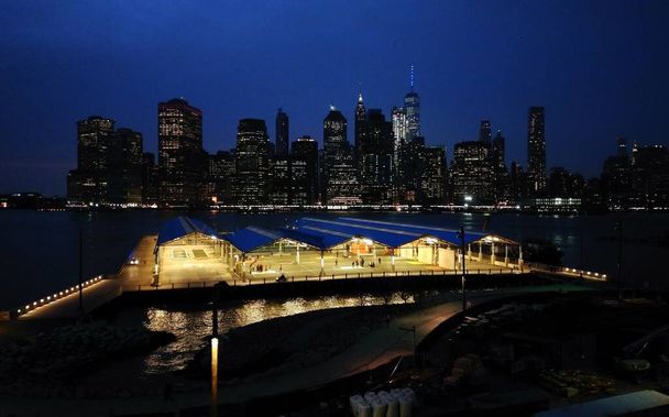 Brooklyn 'den East River' a uzanan Lower Manhattan siluetinin gece görüşü, Brooklyn tarafında halka açık atletizm sahaları ön cephede, New York, New York, ABD - 5 Nisan 2017 - Fotoğraf, Görsel