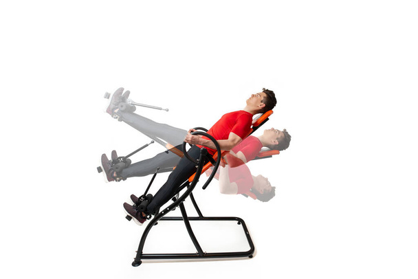 Man doing exercise on inversion table for his back pain, isolate - Photo, Image