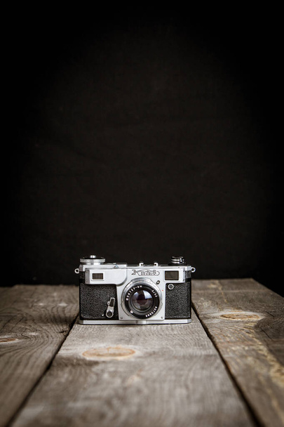 Old vintage photo camera with black background on a wooden table - Photo, Image