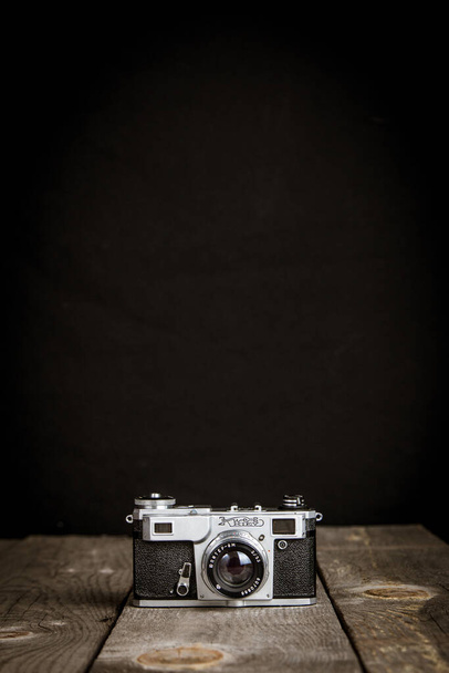 Oude vintage fotocamera met zwarte achtergrond op een houten tafel - Foto, afbeelding