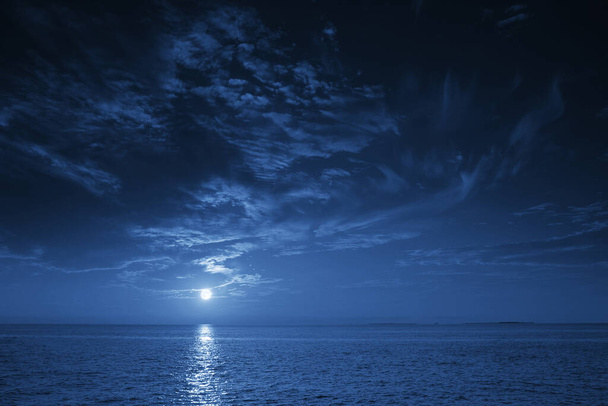 This photo illustration of a deep blue moonlit ocean at night with calm waves would make a great travel background for any coastal region or vacation, emphasizing the beauty of the night time ocean or sea. - Photo, Image