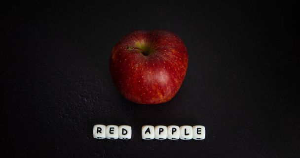 rode appel met wit schrift op donkere achtergrond - Foto, afbeelding