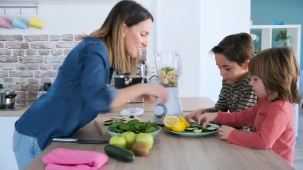 Video of two boys helping his mother to prepare a detox juice with blender in the kitchen at home. - Video, Çekim