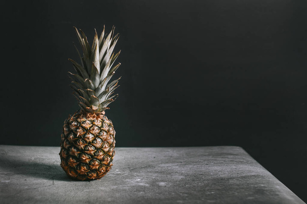 Beautiful pineapple in a studio on a stone surface - Фото, изображение