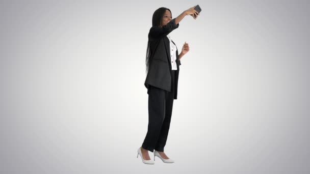 Kaunis afroamerikkalainen nainen hymyilee hänen puhelimensa ammunta selfie kaltevuus taustalla
. - Materiaali, video
