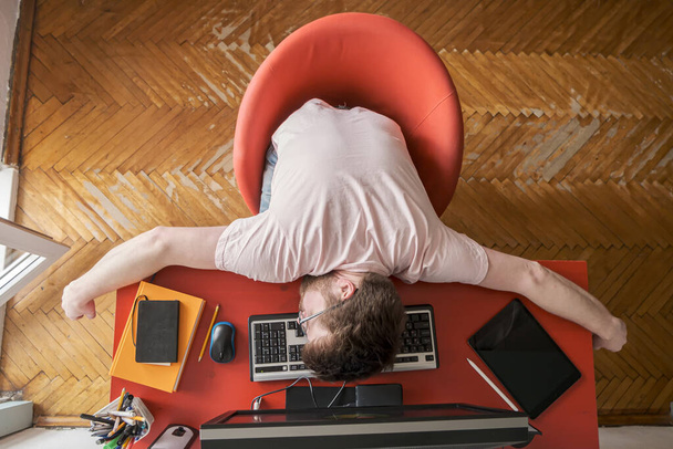 Muž spí na klávesnici, pracuje doma na dálku na počítači. Pojem sebeizolace během pandemie. Moderní životní styl. - Fotografie, Obrázek