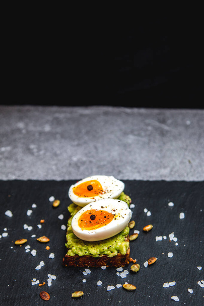 Zdravý avokádový toast s vejci k snídani na černém talíři - Fotografie, Obrázek