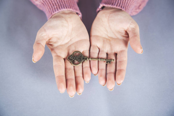 woman hand holding key on the gray desk background - Foto, imagen