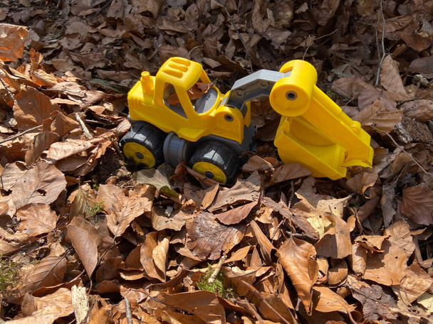 Une excavatrice jouet dans un tas de feuilles par un matin de printemps ensoleillé
 - Photo, image