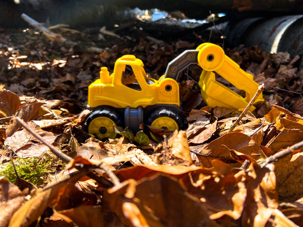 A toy excavator in a pile of leaves on a sunny spring morning - Photo, Image