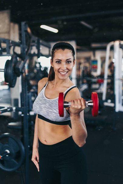 Young fit and attractive woman working out in modern gym with dumbell - Fotoğraf, Görsel