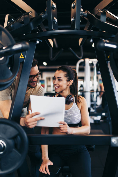 Young fit and attractive woman working out in modern gym together with her personal fitness instructor or coach. - Foto, Imagem